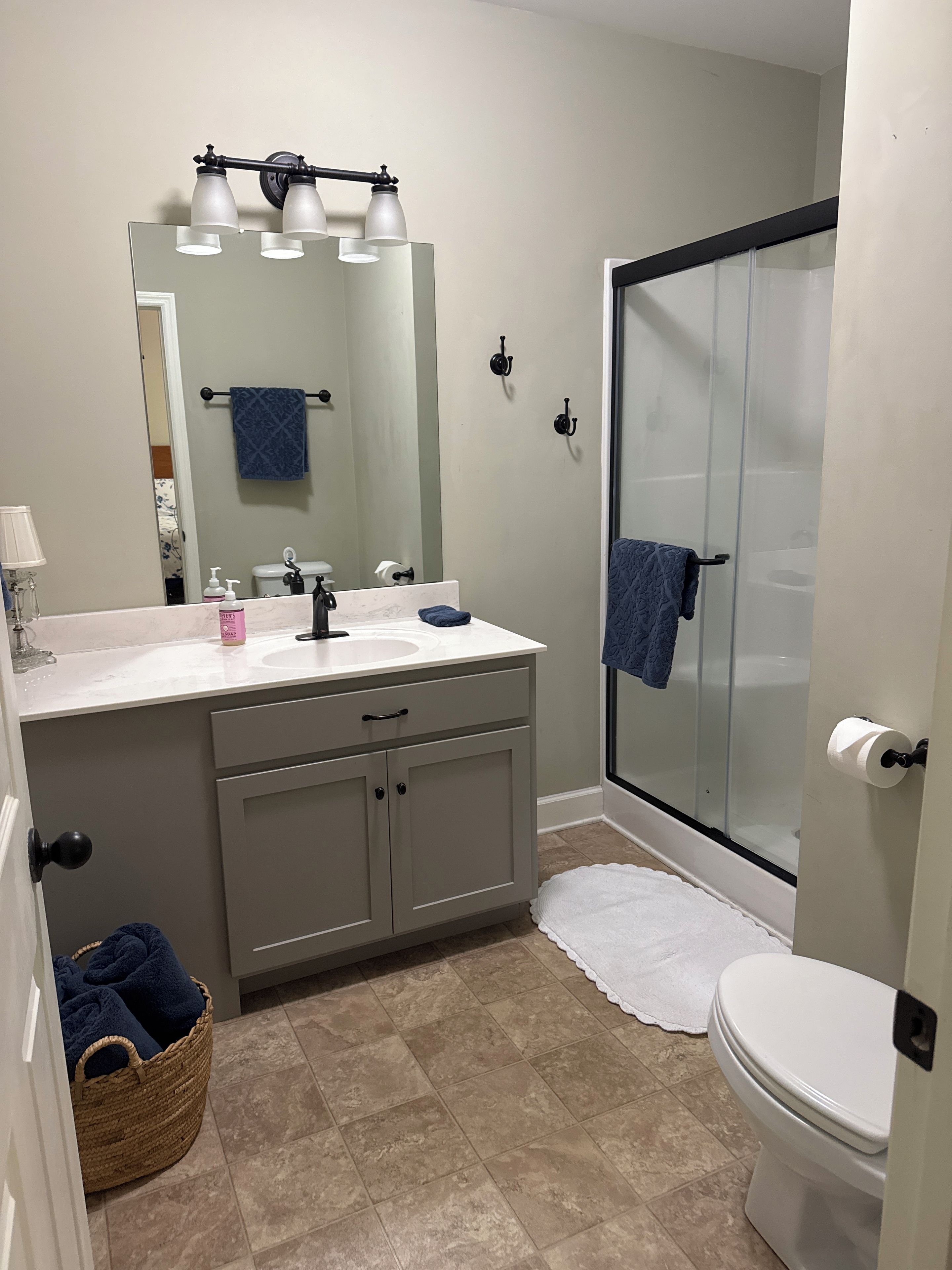A bathroom with a white sink, a mirror, a glass shower enclosure, and a white toilet.
