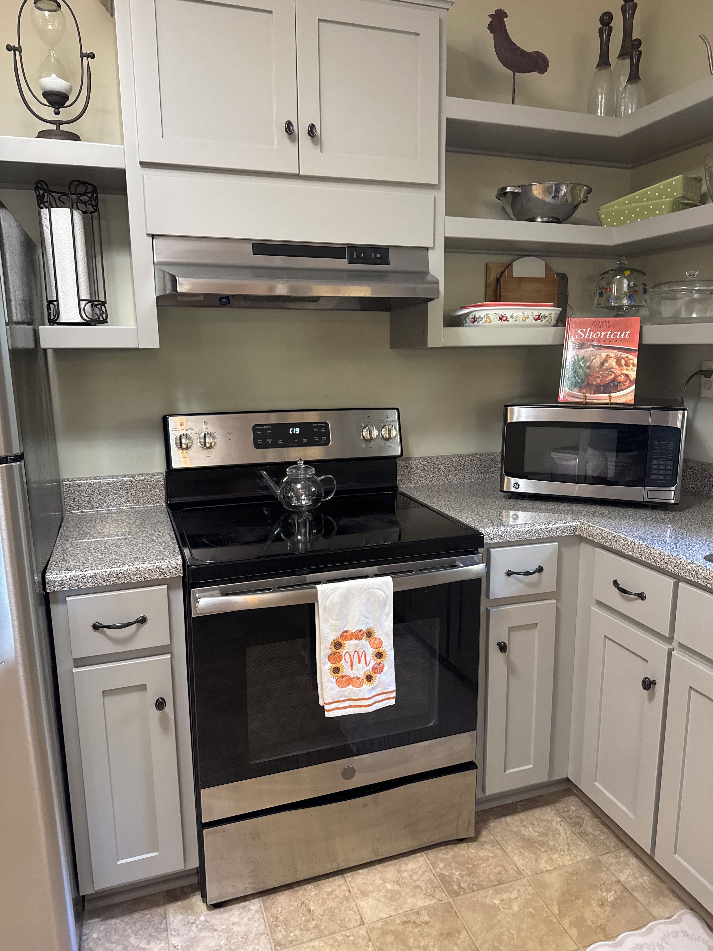 A kitchen with a stove, oven, microwave, and various kitchenware.