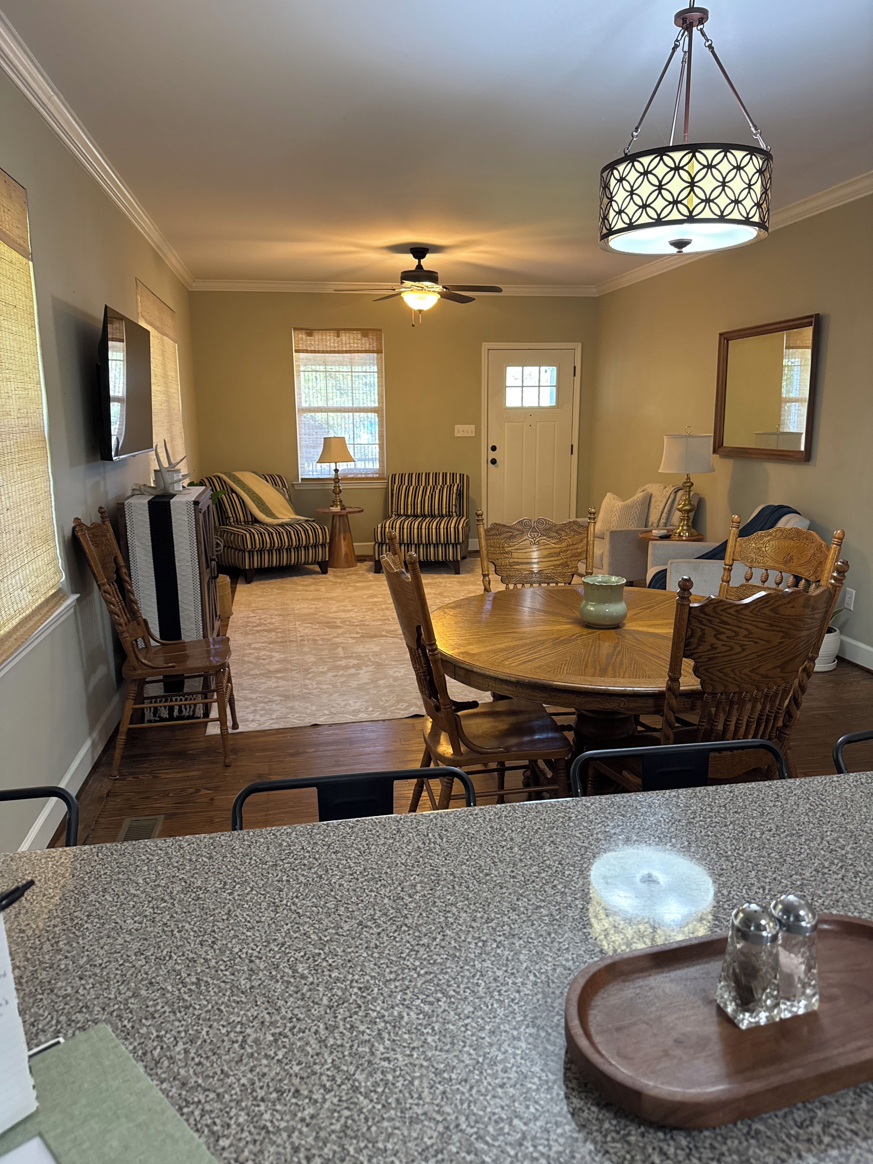 A dining area with a round table, chairs, and a ceiling fan.