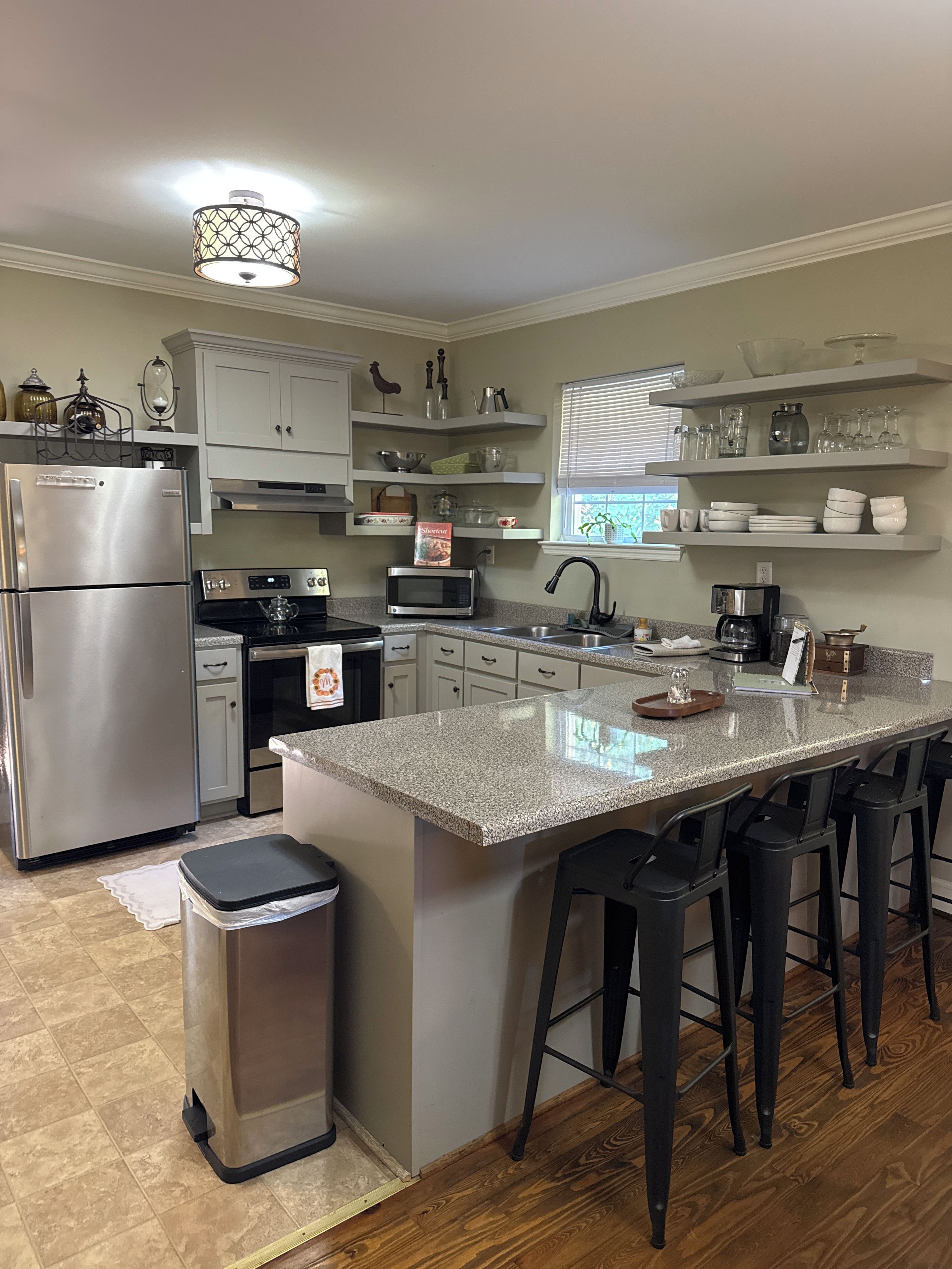 A modern kitchen with a central island, stainless steel appliances, and bar stools.