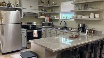 A modern kitchen with a central island, stainless steel appliances, and bar stools.