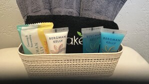 Cesto com toalhas, uma bolsa preta e produtos de cuidados Bergman Kelly.