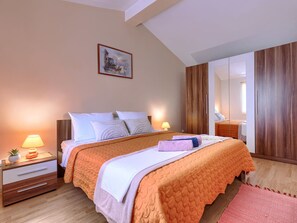 Un dormitorio con una cama, mesitas de noche, una lámpara, un espejo y un cuadro en la pared.