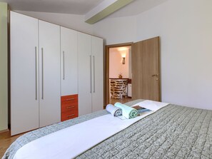 A bedroom with a bed, a wardrobe, and a door leading to a bathroom. - Nevenka by Interhome (Barban)