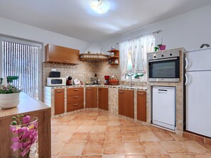 A kitchen with wooden cabinets, a microwave, a stove, a sink, and a refrigerator. - Nevenka by Interhome (Barban)