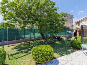 A backyard with a swing set, a small tree, and a patio area. - Nevenka by Interhome (Barban)