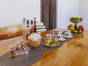 Una mesa de comedor con diversos objetos, incluyendo botellas, un florero, un frutero y un juego de té.