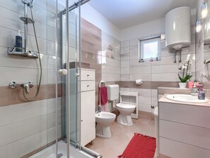 Un baño moderno con cabina de ducha de vidrio, inodoro, bidé, lavabo y espejo.