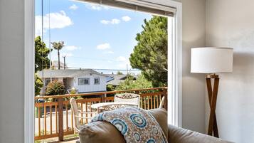 A room with a view of a residential area, a wooden deck, and a lamp.
