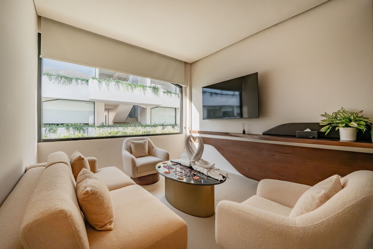 Una sala moderna con un sofá, sillones, una mesa de centro y un televisor de pantalla plana montado en la pared.