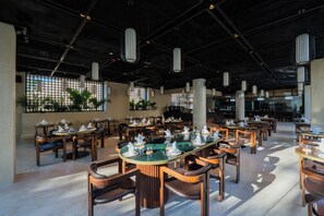 Un comedor amplio con techos altos, iluminación colgante moderna y una mesa central rodeada de sillas.