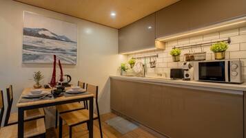 A modern kitchen with a dining area, featuring a wooden table, chairs, a microwave, and potted plants.