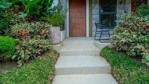 A stone staircase leading to a wooden door, surrounded by lush greenery and a black chair. - Ohhana Lofts El Nido (El Nido)