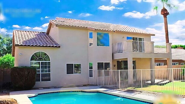 Ein zweigeschossiges Haus mit Swimmingpool, Balkon und einer hohen Palme.