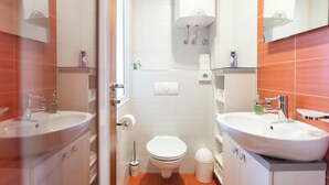 Un baño moderno con dos lavamanos, inodoro, ducha y espejo.