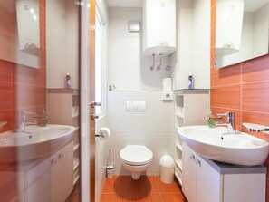 Un baño moderno con dos lavamanos, inodoro, ducha y espejo.