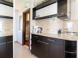 Una cocina moderna con armarios oscuros, una encimera, una cafetera y un lavabo.