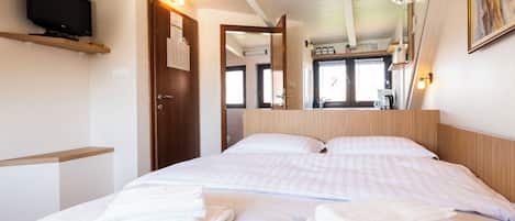 Una habitación de hotel con una cama, televisión, cabecero de madera y aire acondicionado de pared.
