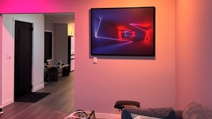Ein modernes Wohnzimmer mit einem zeitgenössischen abstrakten Gemälde, einem Fernseher mit schwarzem Rahmen und einem grauen Sofa.