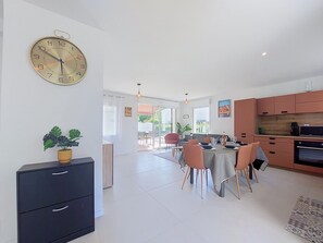 A modern kitchen with a dining area, a clock on the wall, and a view to the outside. - Carin'et by Interhome (Saint Palais sur mer)