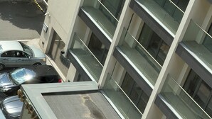 A multi-story building with a parking garage, glass railings, and a car parked on the ground floor. - Limons Apartment: Living Room and Bedroom in Downtown Bucharest (București)