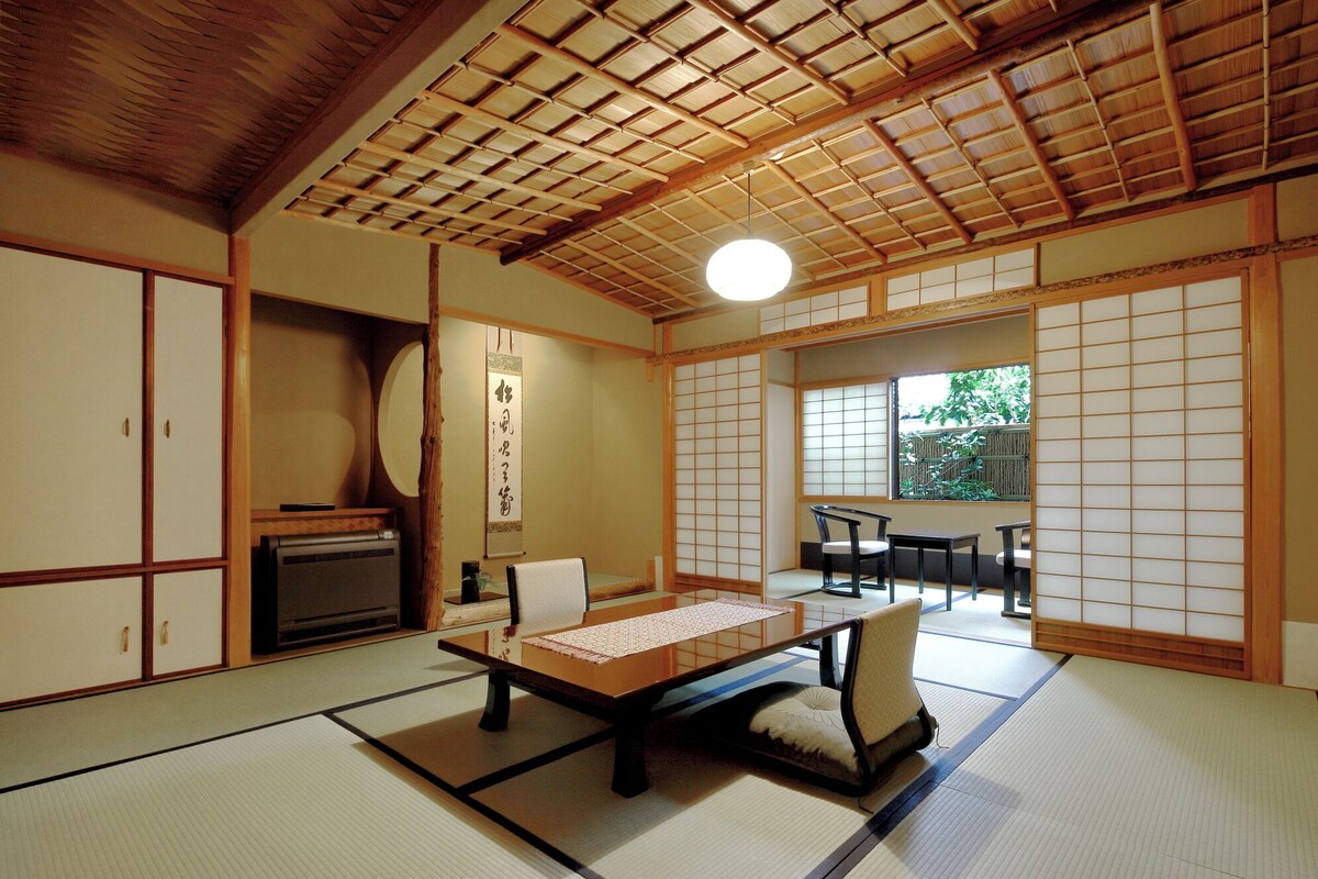A traditional Japanese room with tatami flooring, a low table, a chair, and sliding doors.