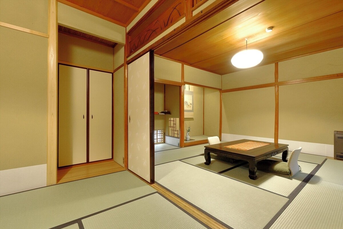 A traditional Japanese room with tatami flooring, a low table, and sliding doors.