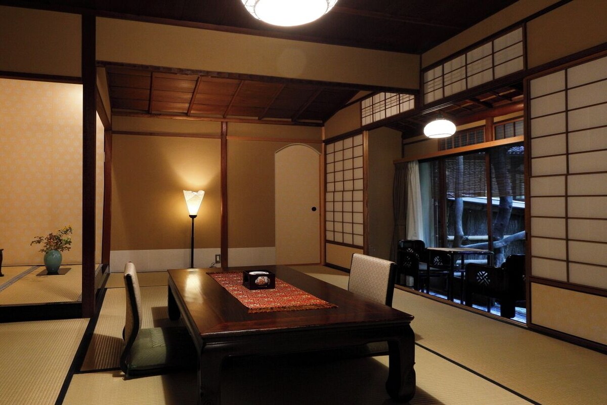 A traditional Japanese room with tatami flooring, a low table, and sliding doors.