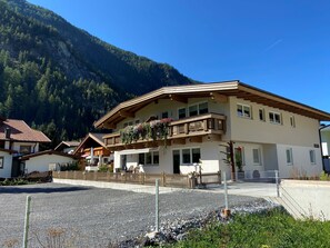 Un bâtiment à deux étages doté d’un balcon, entouré d’une zone recouverte de gravier et d’une clôture en bois.