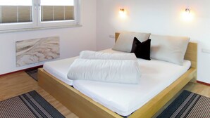Ein Schlafzimmer mit einem Bett, zwei Nachttischlampen, einem Fenster mit Jalousien und einem Marmorbild an der Wand.