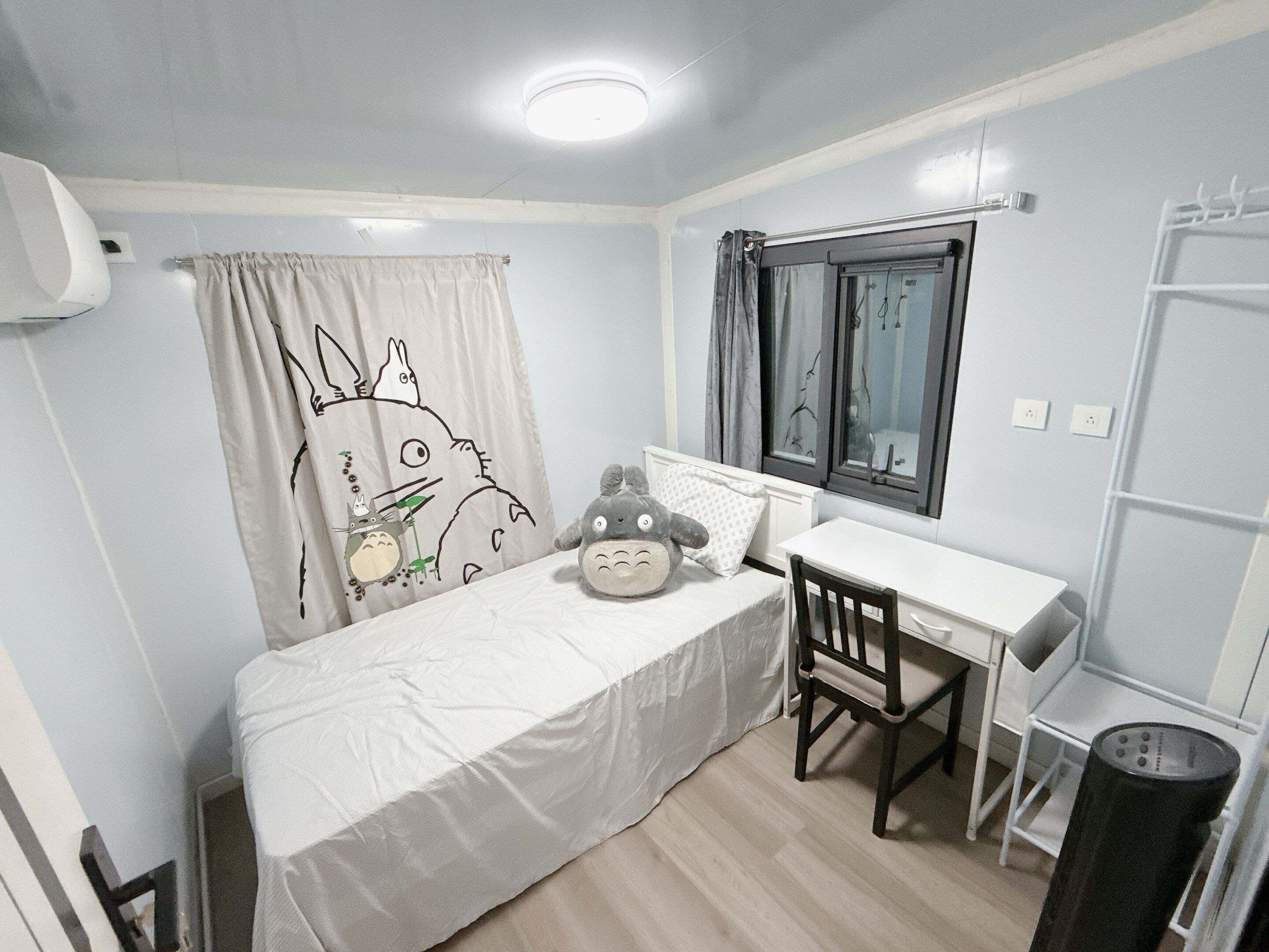 Een slaapkamer met een bed, bureau, stoel, raam en radiator.