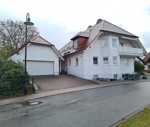 Ein zweistöckiges Wohnhaus mit Garage, Balkon und Auffahrt.
