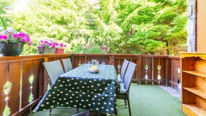 Eine Terrasse im Freien mit einem für zwei Personen gedeckten Tisch, umgeben von Stühlen und einem Holzzaun.