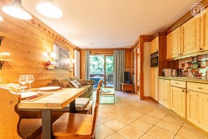 A wooden interior with a dining area, kitchen, and a view through a glass door.