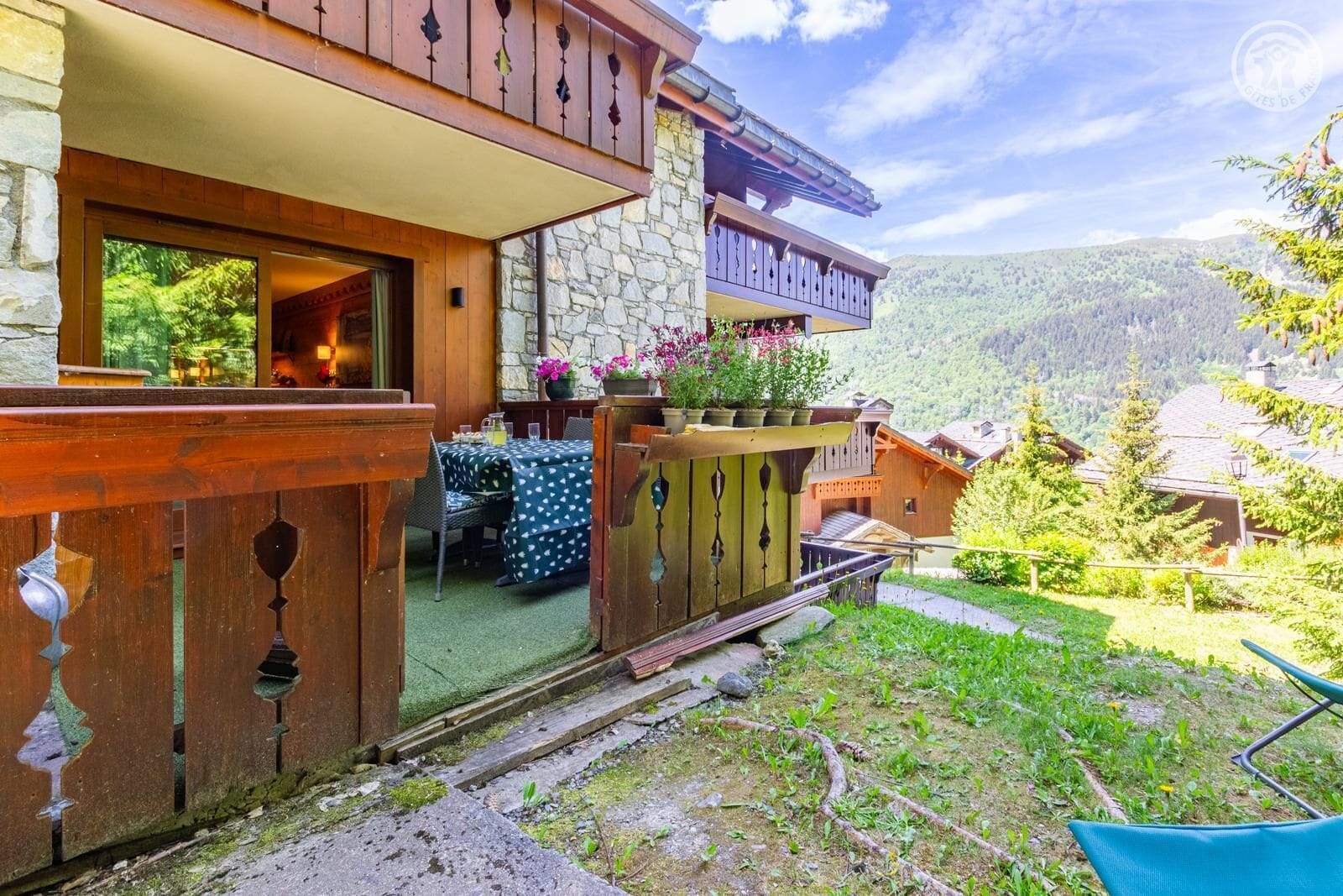 A chalet with a stone facade, wooden balcony, and a view of the surrounding mountains.
