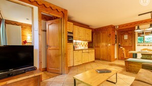 Ein Holzinterieur mit Fernseher, Holzschränken, Fliesenboden und Essbereich.