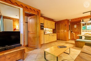 Ein Holzinterieur mit Fernseher, Holzschränken, Fliesenboden und Essbereich.