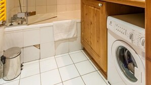 Ein Badezimmer mit Dusche, Badewanne, Waschmaschine und einem Holzschrank.