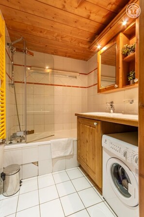 Ein Badezimmer mit Dusche, Badewanne, Waschmaschine und einem Holzschrank.