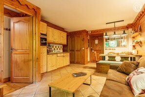 A wooden interior with a dining area, sofa, and a tiled floor.