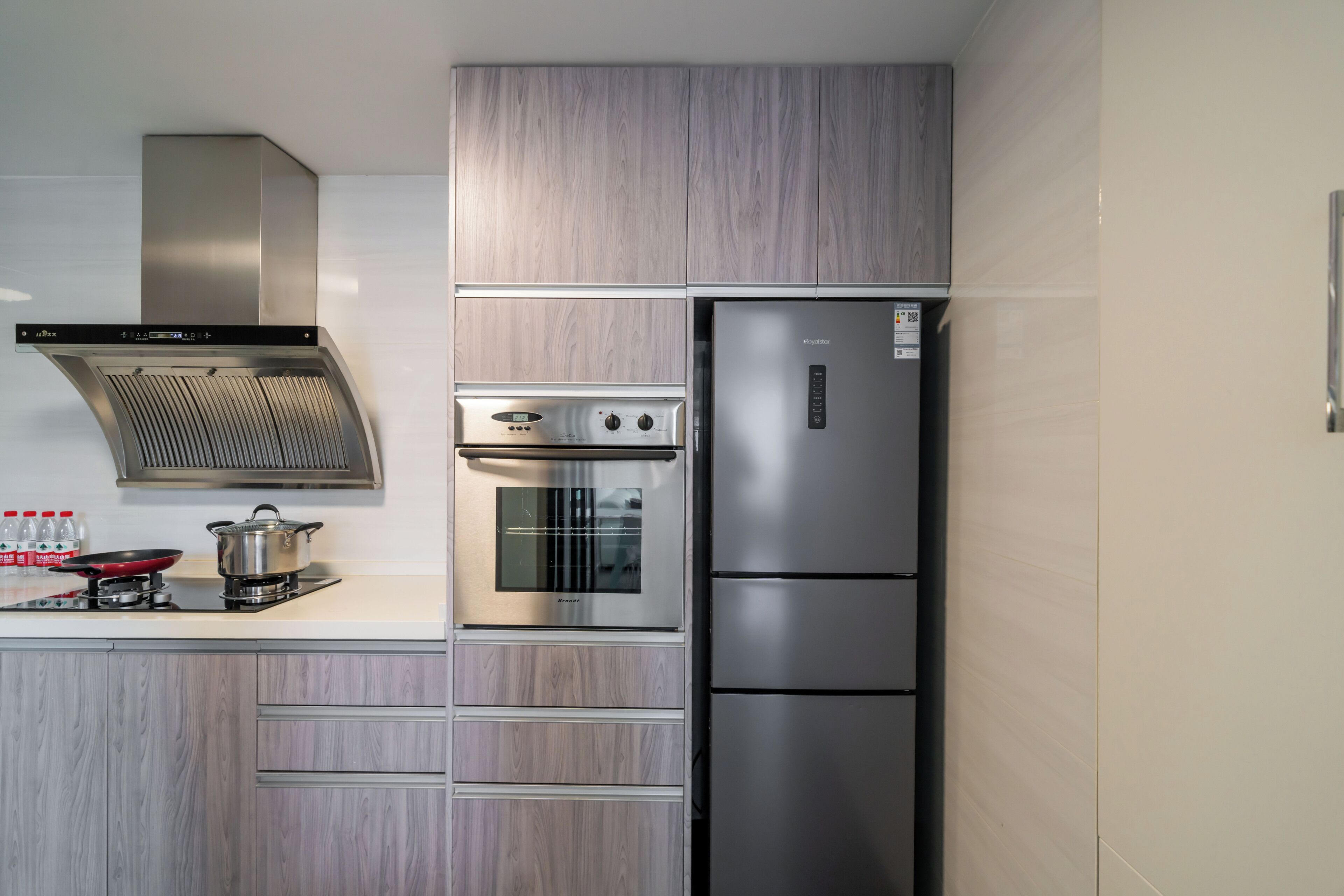 Une cuisine moderne dotée d’appareils électroménagers en acier inoxydable, d’un four encastré et d’un réfrigérateur à deux portes.