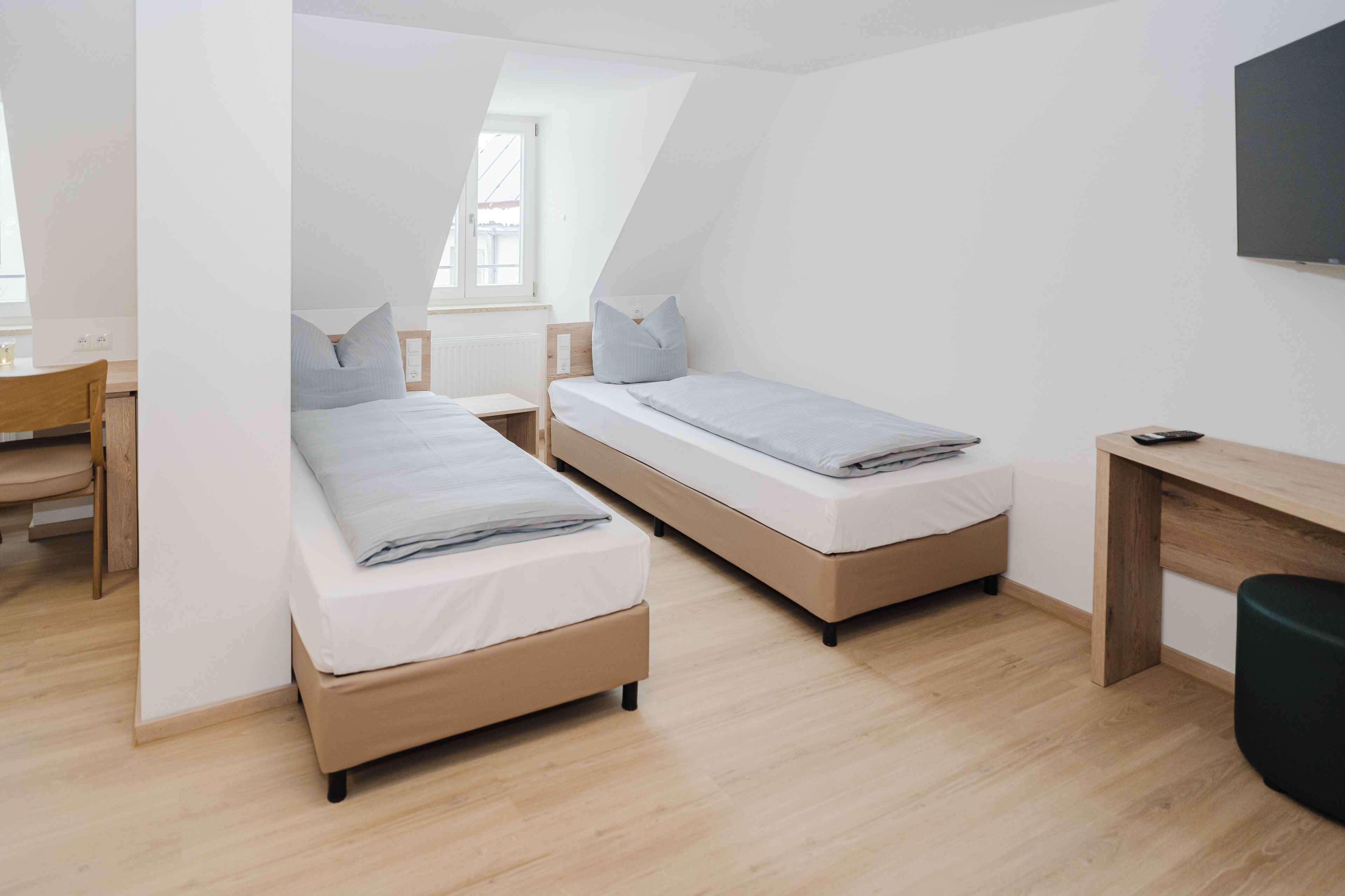 Una habitación con dos camas, un escritorio y una silla.