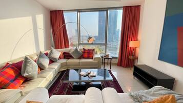 Ein modernes Wohnzimmer mit einer Couch, einem Couchtisch und Blick auf die Stadt durch große Fenster.