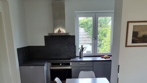Eine moderne Küche mit Essbereich, Holzboden und einem Fenster mit Blick auf Grünflächen.