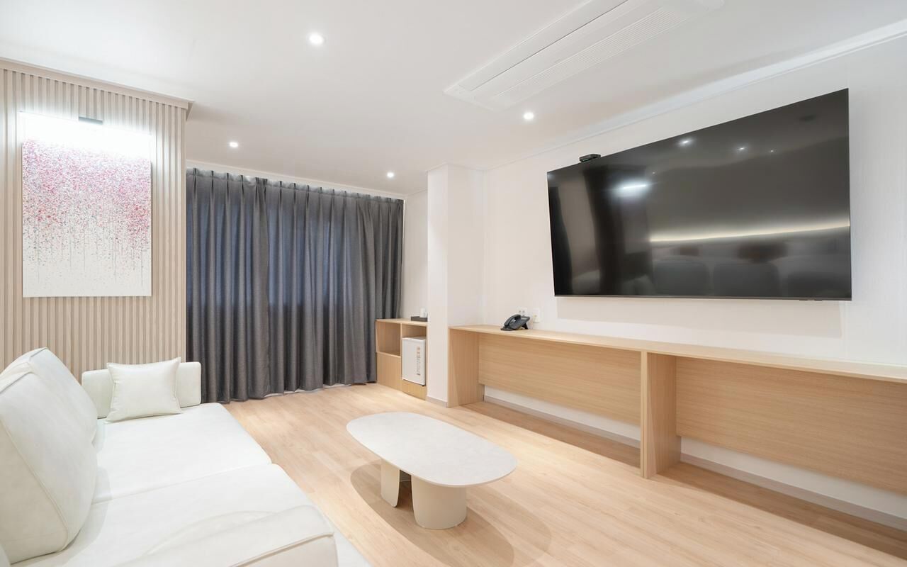 Una sala de estar moderna con un televisor de pantalla plana grande, un sofá, una mesa de centro y un mueble para TV.