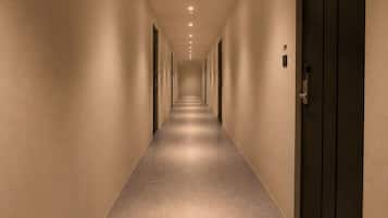Un pasillo largo y estrecho con puertas a ambos lados y piso alfombrado.