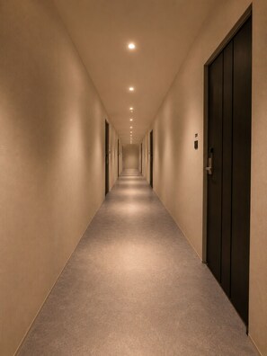 Un pasillo largo y estrecho con puertas a ambos lados y piso alfombrado.