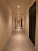 Un pasillo largo y estrecho con puertas a ambos lados y piso alfombrado.