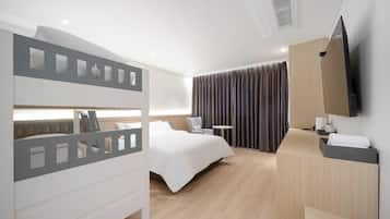 Een moderne hotelkamer met een stapelbed, een bureau, een stoel, een flatscreen televisie en een groot raam met gordijnen.