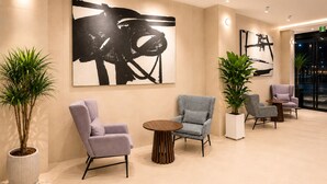 Un hall d’entrée moderne, doté de sièges, d’œuvres d’art et de plantes en pot.